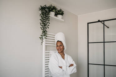 Thoughtful woman standing with arms crossed in bathroom at home - EBBF07903