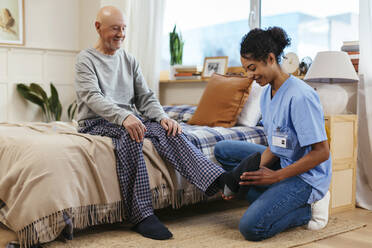 Physiotherapeutin untersucht den Knöchel eines älteren Mannes während einer Physiotherapie-Sitzung - EBSF02678