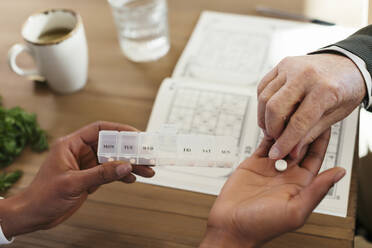 Hand of man taking pill from caretaker - EBSF02695