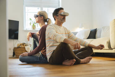 Älteres Paar mit Virtual-Reality-Headset sitzt Rücken an Rücken zu Hause - JOSEF16642