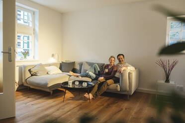 Ehemann und Ehefrau sitzen auf dem Sofa im Wohnzimmer zu Hause - JOSEF16665