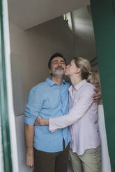 Reife Frau küsst Ehemann stehend zu Hause - JOSEF16671