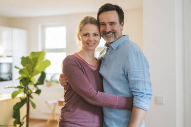 Smiling wife embracing mature man at home - JOSEF16728