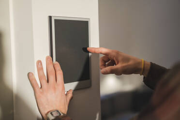 Man touching smart home device on wall at home - JOSEF16738