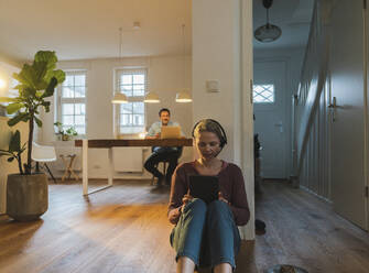 Mature businesswoman working through tablet PC sitting near wall at home office - JOSEF16741