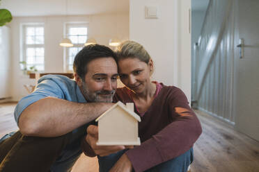 Ehemann und Ehefrau betrachten ein Hausmodell, das zu Hause sitzt - JOSEF16750