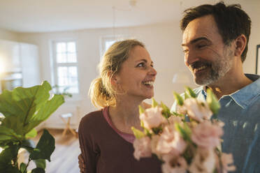 Glücklicher Ehemann überrascht Frau mit Blumen zu Hause - JOSEF16755
