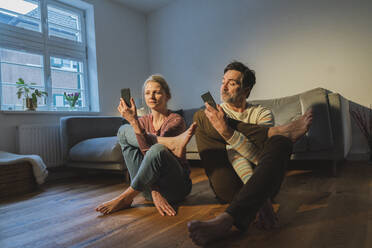 Pärchen mit Smartphones übt Yoga im Wohnzimmer - JOSEF16795