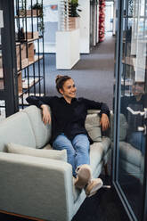 Geschäftsfrau entspannt auf Couch im Büro - JOSEF16860