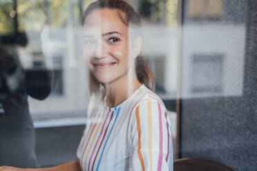 Lächelnde nachdenkliche Geschäftsfrau durch Glas gesehen - JOSEF16872