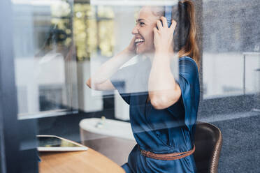 Happy young businesswoman wearing headset in soundproof cabin - JOSEF16876