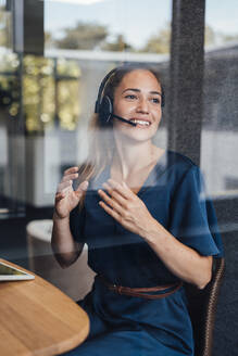 Glückliche Geschäftsfrau im Gespräch mit Headset in schalldichter Kabine im Büro - JOSEF16879