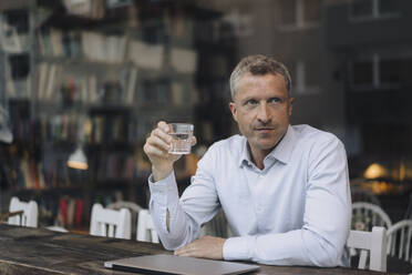Geschäftsmann mit einem Glas Trinkwasser in einem Café sitzend - KNSF09642