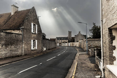 Sunlight streaming through clouds over empty street in old town - CHPF00859