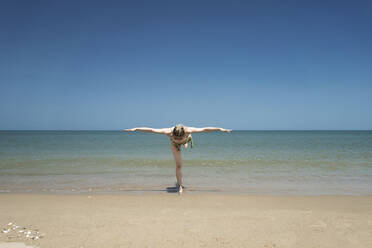 Woman with arms outstretched standing at beach - CHPF00868
