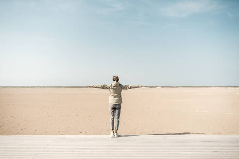 Woman standing with arms outstretched on beach - CHPF00873