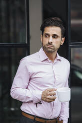 Nachdenklicher Geschäftsmann steht mit Kaffeetasse vor der Tür - JOSEF16890