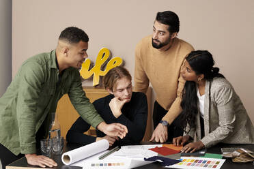 Multiracial fashion designers discussing in meeting at office - RSKF00046