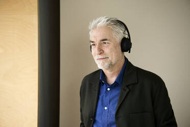 Contemplative mature man wearing wireless headphones - RSKF00092