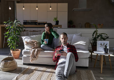 Mann und Frau sitzen mit Getränken im heimischen Wohnzimmer - VEGF06204