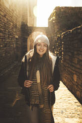 Smiling young woman standing on footpath on a sunny day - ACPF01545