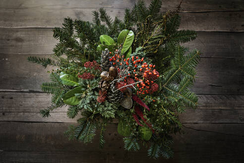 Autumnal arrangement of twigs, laurel, amaranthus, skimmia, rose hips and pine cones - EVGF04284