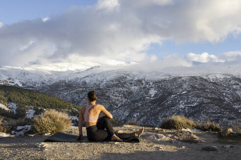 Woman doing yoga on mountain under cloudy sky - LJF02473