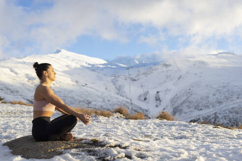 Frau meditiert auf schneebedecktem Berg - LJF02475