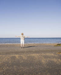 Ältere Frau bewundert das Meer am Strand an einem sonnigen Tag - UUF28160
