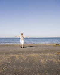 Elderly woman admiring sea at beach on sunny day - UUF28160