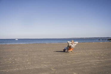 Elderly woman relaxing and looking at sea on sunny day - UUF28177