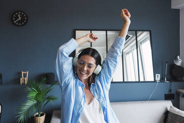 Happy woman dancing and listening to music at home - PNAF04989