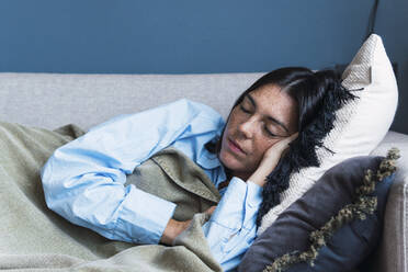 Young woman sleeping on sofa at home - PNAF04991