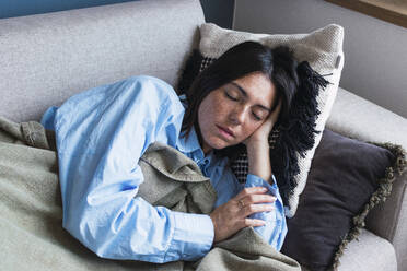 Young woman with eyes closed resting on sofa at home - PNAF05008