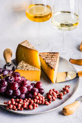 Von oben Käsevariation mit frischen Früchten auf der Steinplatte und Weißwein im Glas auf dem Betontisch - ADSF43117