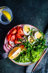 Healthy raw vegetable salad with seeds and boiled eggs served in the bowl on concrete table - ADSF43121