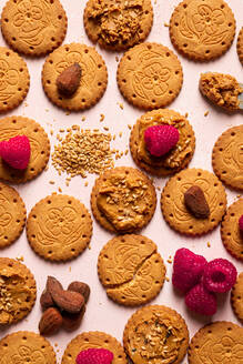 Draufsicht auf appetitliche knusprige Kekse mit Erdnussbutter mit Sesam Himbeeren und Nüssen auf dem Tisch als abstrakten Hintergrund serviert - ADSF43130