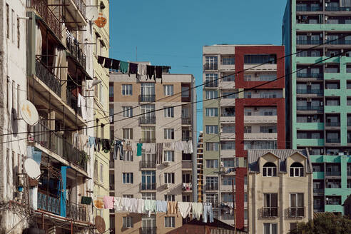 Außenansicht eines Hochhauses mit elektrischen Drähten und Wäsche, die an Seilen an einem sonnigen Tag im Ghetto von Batumi, Georgien, trocknet - ADSF43163