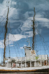 Reflexion im kräuselnden Meerwasser des vertäuten Schiffes und blauer bewölkter Himmel an einem sonnigen Tag - ADSF43209