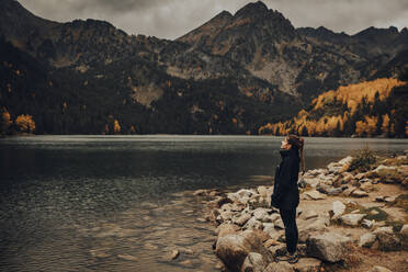 Girl in a jacket breathing fresh air by a lake in winter - CAVF96584