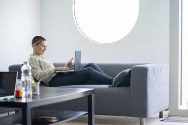 Businesswoman doing video call on laptop at home office - FBAF02010