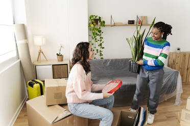 Excited friends unpacking box at home - JCZF01163