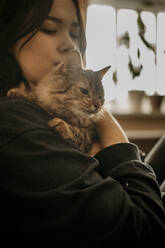 Teenage girl holding cat in arms - ANAF00972