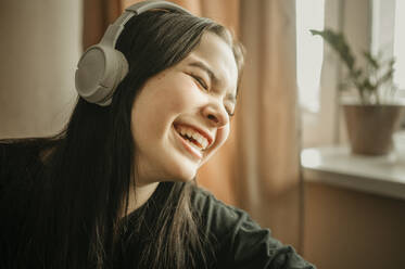 Cheerful girl listening to music through headphones - ANAF00974