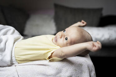 Cute baby boy stretching arms lying on sofa - NJAF00220