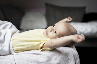Niedlicher Babyjunge streckt Arme auf dem Sofa liegend aus - NJAF00220