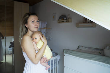 Contemplative mother with baby boy standing at home - NJAF00230
