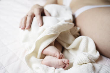 Baby boy lying by mother on bed - NJAF00233