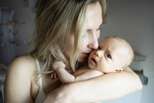 Mother kissing baby boy at home - NJAF00236