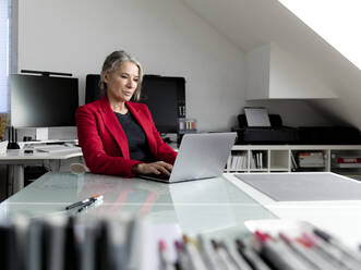 Geschäftsfrau arbeitet am Laptop am Schreibtisch im Büro - FLLF00837